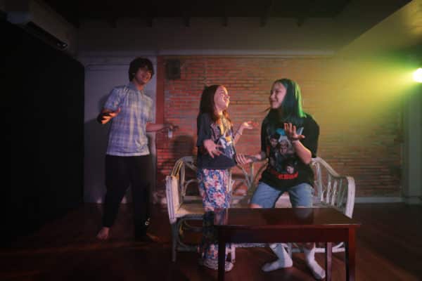 roup of teenagers laughing and rehearsing a scene in a vibrant Bangkok classroom